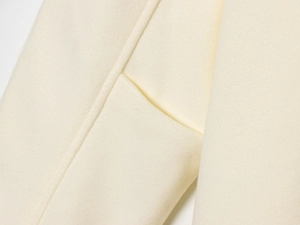 Detailed macro view of the premium cream wool coat showing stitching and fabric texture
