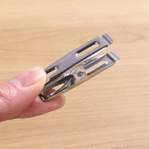 Multi-purpose stainless steel clothespin held in hand showing compact size and shiny finish