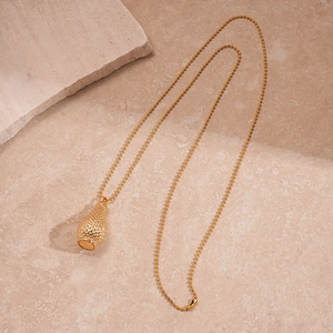 Gros plan du collier pendentif bouteille vintage doré sur un fond de pierre naturelle