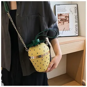 Détail du sac seau en forme de fraise jaune avec rivets noirs et couvercle en feuilles