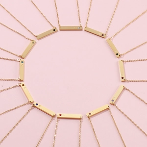 Minimalist gold horizontal bar necklaces with colorful birthstones on pink background