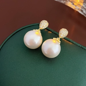 Dettaglio ravvicinato di orecchini di perle placcati in oro con accenti di zircone lucido