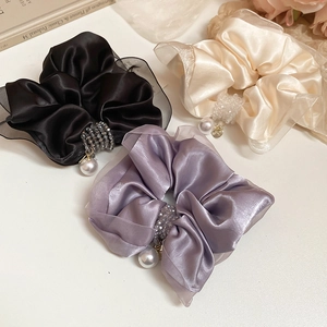 Detailed set of three satin hair scrunchies with pearls and crystal charms on white background