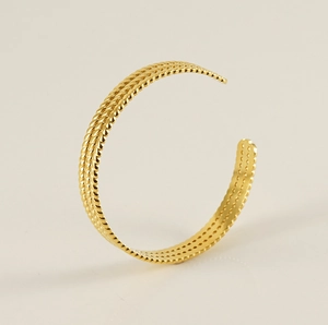 Détail d'un bracelet ouvert en acier titane doré avec un design de corde torsadée