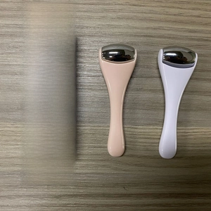 Mini dual-color facial roller massagers with silver heads and packaging on wood surface