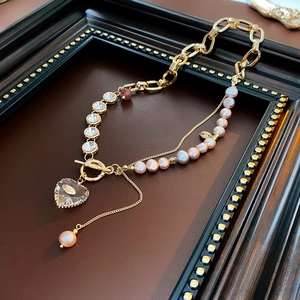 Detail of gold chain necklace with pink freshwater pearls and large heart crystal pendant