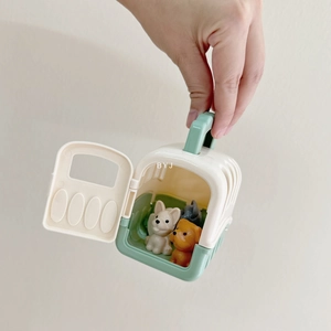 Green toy pet carrier with three puppy figures being held by a hand for pretend play