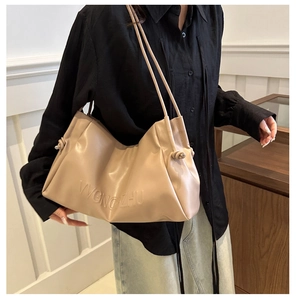 Close-up of beige soft leather tote bag featuring pleated cloud design and thin straps