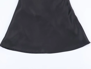 Close-up of black satin dress hem showing high-quality sewing and smooth fabric texture