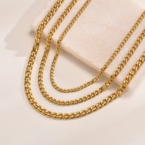 Tre dimensioni di catene a maglie cubane in acciaio dorato su display in marmo beige