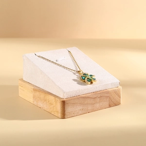 Elegant gold necklace with green flower pendant and micro-inlaid diamonds on beige background