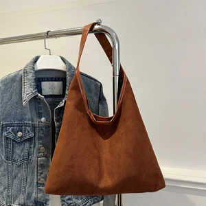 Brown suede tote shoulder bag with a triangular design hanging on a metal rack