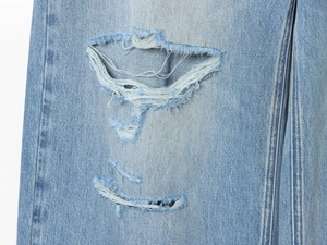 Dettaglio ravvicinato della trama strappata su tessuto denim jeans blu chiaro