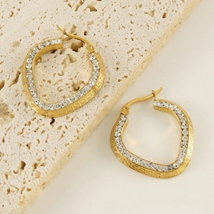 Detail of 18K gold heart hoop earrings featuring zircons and Greek key engraving