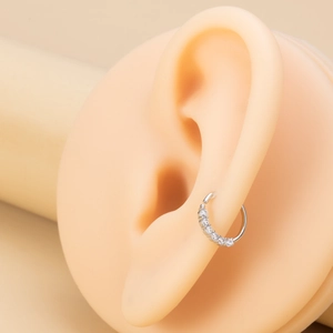 Macro shot of silver crescent moon helix earring with zircon studs on ear model