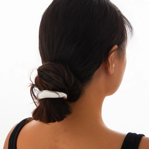 Detail of silver geometric square hair tie on dark brown bun, minimalist metallic design