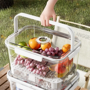 Portable clear picnic storage box with handle and fruit display in outdoor setting
