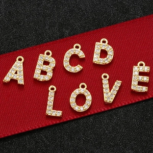Close-up of golden S925 silver CZ letter charms A B C D L O V E on a red ribbon