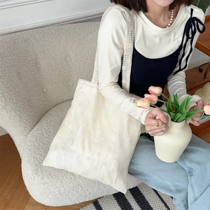 Close-up of white floral lace tote bag with daisy embroidery detail on mesh fabric