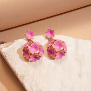 Gros plan de boucles d'oreilles fleurs roses et dorées sur un support en pierre