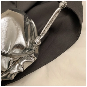 Detail of silver metallic cloud bag featuring pleated faux leather and a knotted strap design