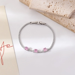 Detailansicht eines Silberarmbands mit rosa quadratischen Zirkonia auf Natursteinhintergrund
