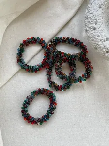 Close-up of handmade crystal beaded hair tie with colorful glass beads on linen texture