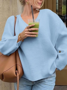 Close-up of casual light blue V-neck knit sweater with loose fit and stylish jewelry detail
