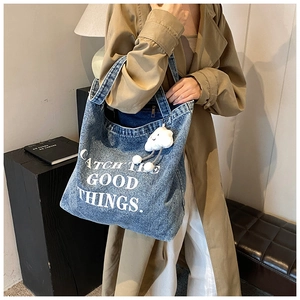 Detail of denim tote bag with Catch The Good Things embroidery and cloud charm