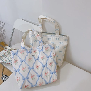 Detailed texture of floral and bow print canvas tote bags on a white chair