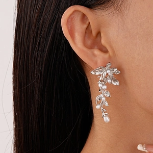 Close-up of elegant silver leaf earrings with inlaid pearls worn by a model
