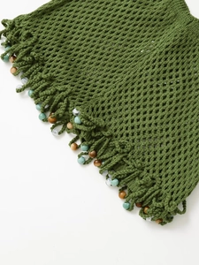 Detail of green crochet fabric with colorful bead tassels and woven mesh texture