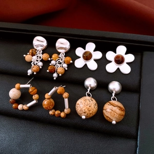 Detailed set of four vintage silver earrings with beads and stones on black tray