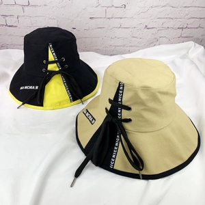 Détail d'un chapeau bob bicolore avec lanières lettrées et œillets métalliques