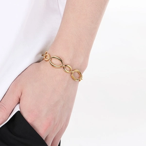 Detailed close-up of a gold oval link chain bracelet worn on a female wrist