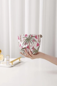 Detail of fabric makeup bag featuring tropical palm tree patterns and floral metal zipper pull