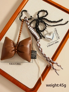 Detailed view of a brown leather bow keychain with silver heart pendant and metal carabiner