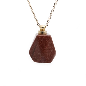 Macro shot of red-brown goldstone perfume bottle pendant with golden metal cap