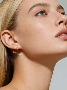 Close-up of 8mm and 9mm gold huggie earrings with cubic zirconia on model's ear