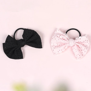 Detailed view of pink and black bow hair ties with hollow polka dot patterns