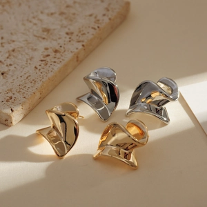 Detailed close-up of minimalist twisted metal stud earrings in gold and silver finishes
