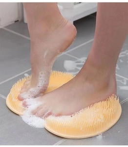 Macro view of feet on yellow silicone scrubbing mat with soapy bristles in a bathroom