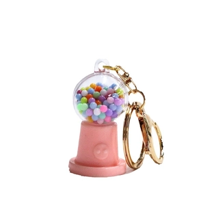 Pink candy machine keychain with colorful beads and golden ring accessory on white background