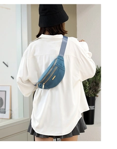 Rear view of a blue nylon waist bag with gold zippers worn over a white shirt
