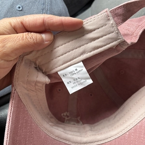 Detail of adjustable cotton strap and interior washing label on pink baseball cap
