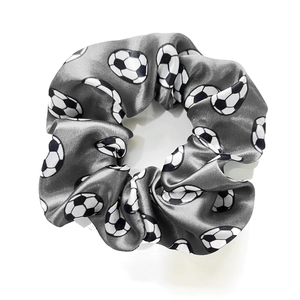 Detailed close-up of grey satin scrunchie with realistic black and white soccer prints