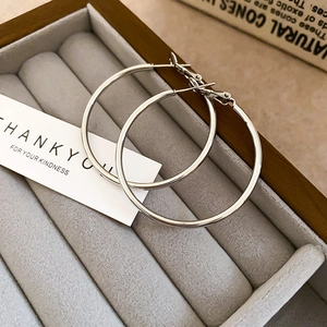 Classic silver hoop earrings displayed in a grey velvet jewelry box with minimalist props