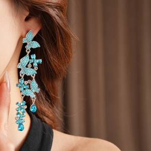 Detail of turquoise butterfly tassel earrings with rhinestones worn by a model