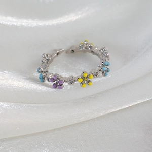 Detail of adjustable silver flower ring with purple and blue enamel and zircon stones