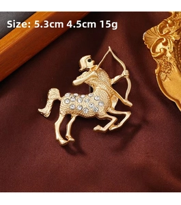 Macro shot of gold Sagittarius brooch with sparkling crystals on dark silk fabric